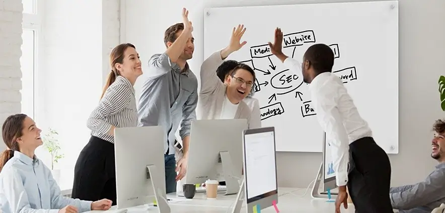 A team is cheering in the office to celebrate excellent teamwork.