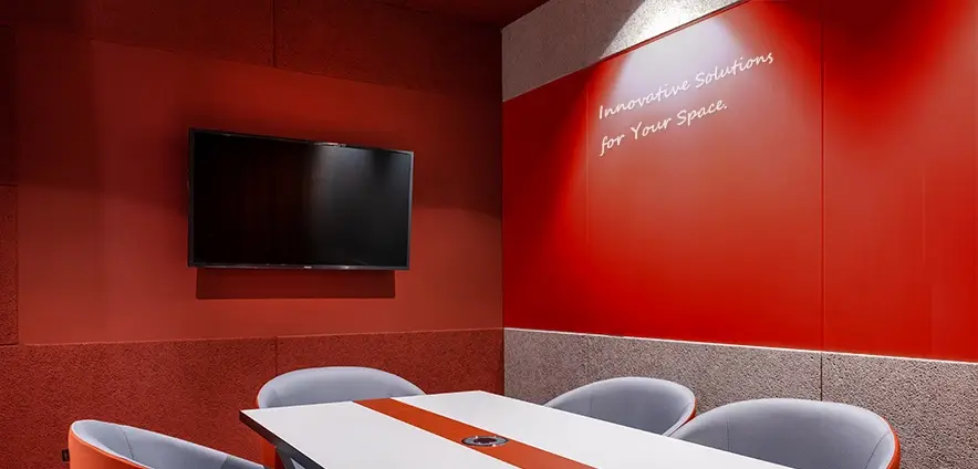A meeting room with red walls, a red glass whiteboard, and a white table setup. The energetic colors can boost brain activity.