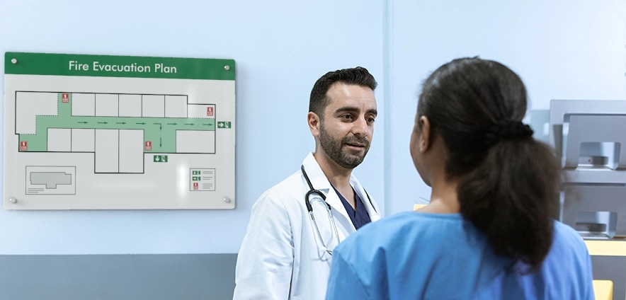 A female nurse is in discussion with a male doctor in front of a whiteboard